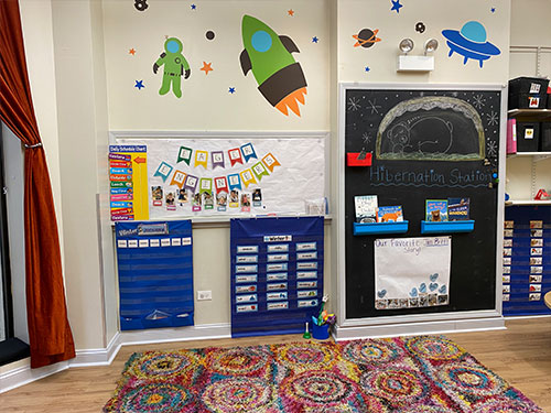 Photo of Urban Child Academy's Gold Coast Three's Room with attendance hangers and chalkboard