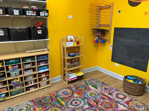 Photo of Urban Child Academy's Gold Coast Three's Room with carpeted area and shelves with toys